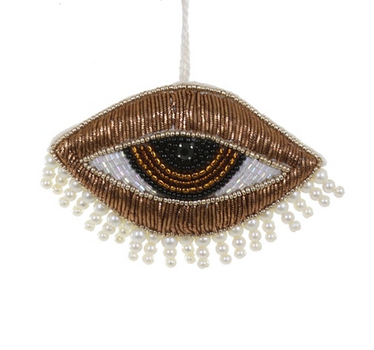 Decorative eye-shaped ornament with beading and pearls on a white background