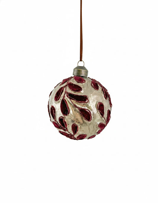 Decorative glass ornament with red leaf patterns on a white background