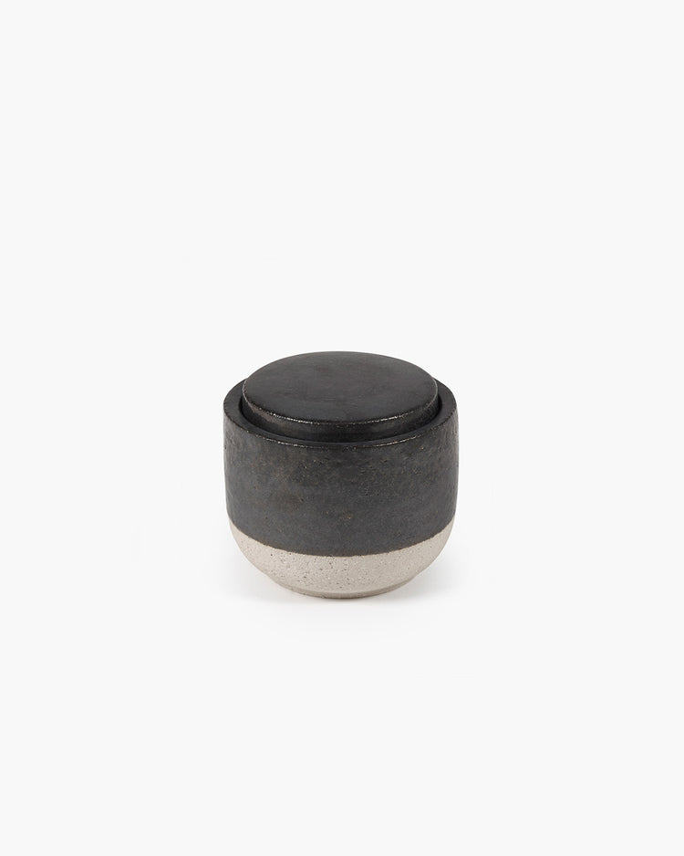 Black ceramic container with a lid on a white background