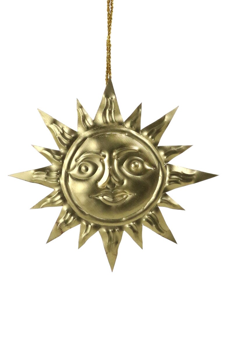 Gold sun-shaped ornament with face on a white background