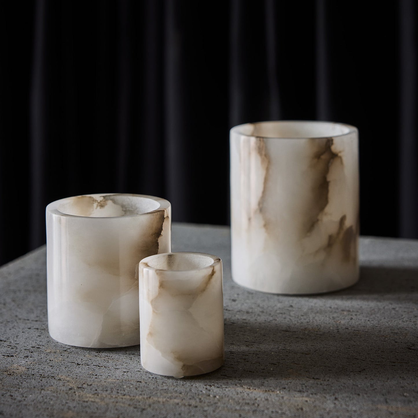 Three marble-textured candle holders on a dark background