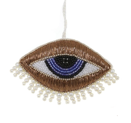 Decorative eye-shaped ornament with beads and pearls on a white background