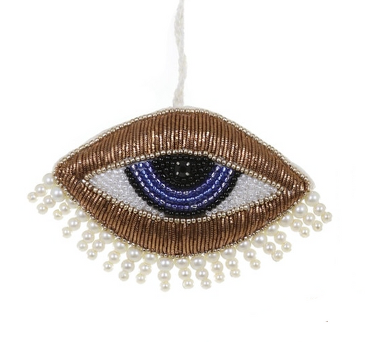 Decorative eye-shaped ornament with beads and pearls on a white background