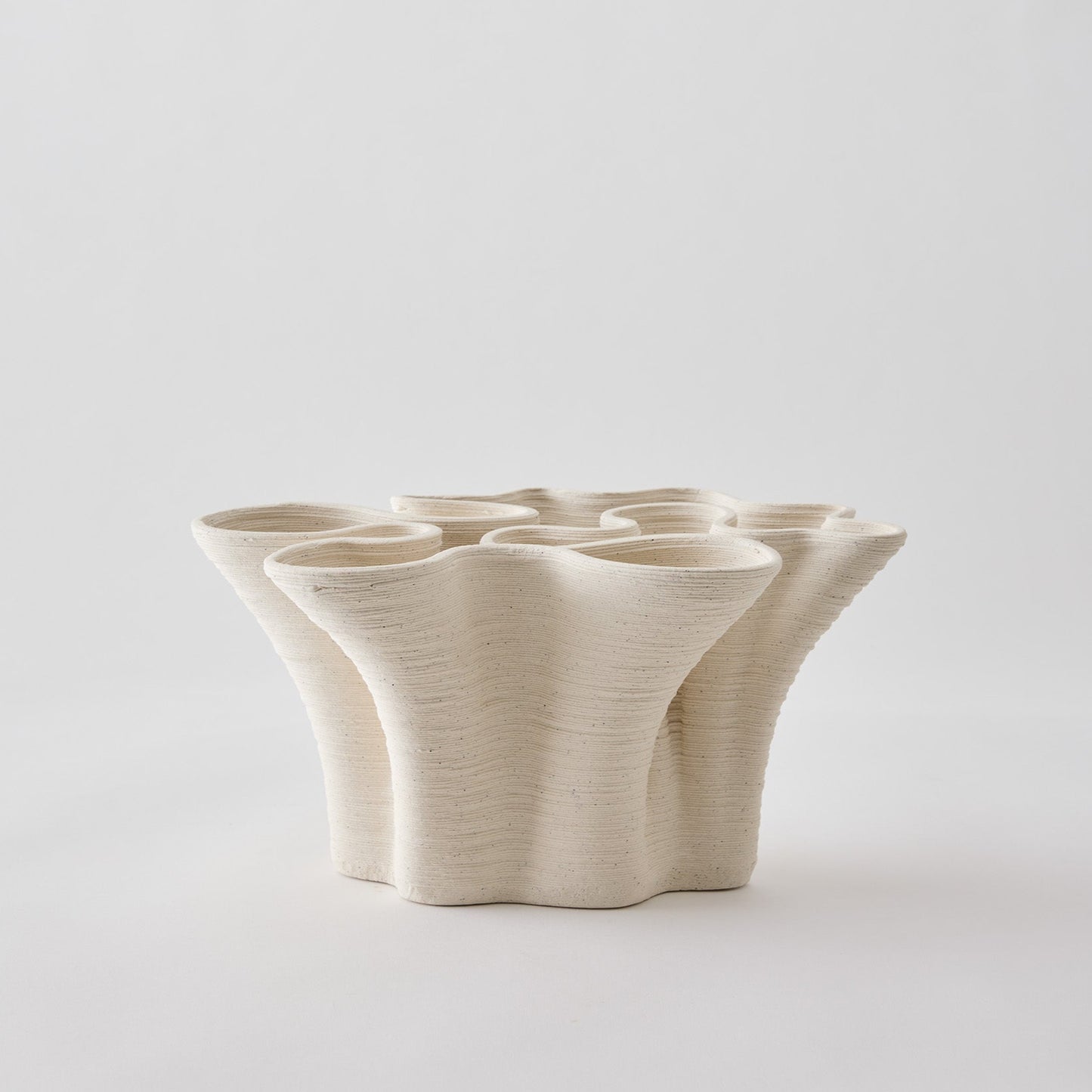 White ceramic vase with a textured surface on a light gray background