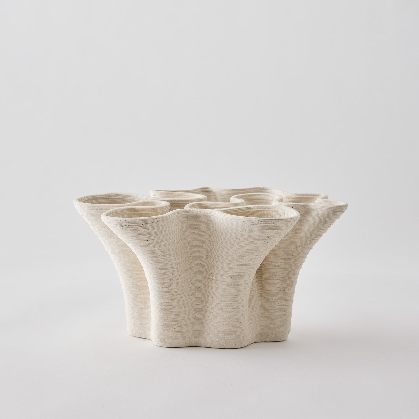 White ceramic vase with a textured surface on a light gray background