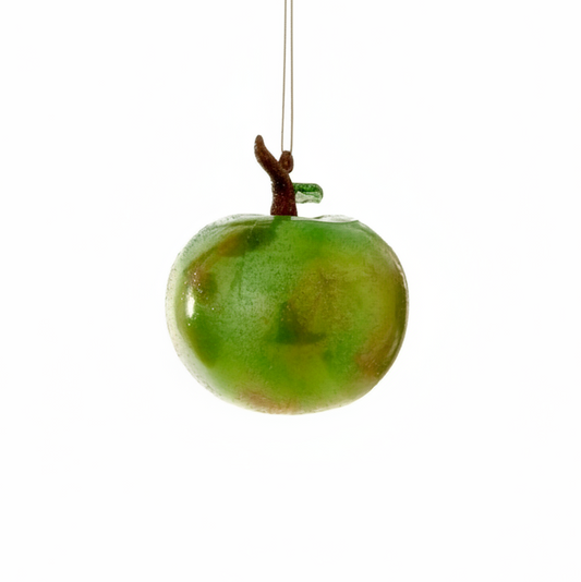 Green apple-shaped ornament with a stem on a white background