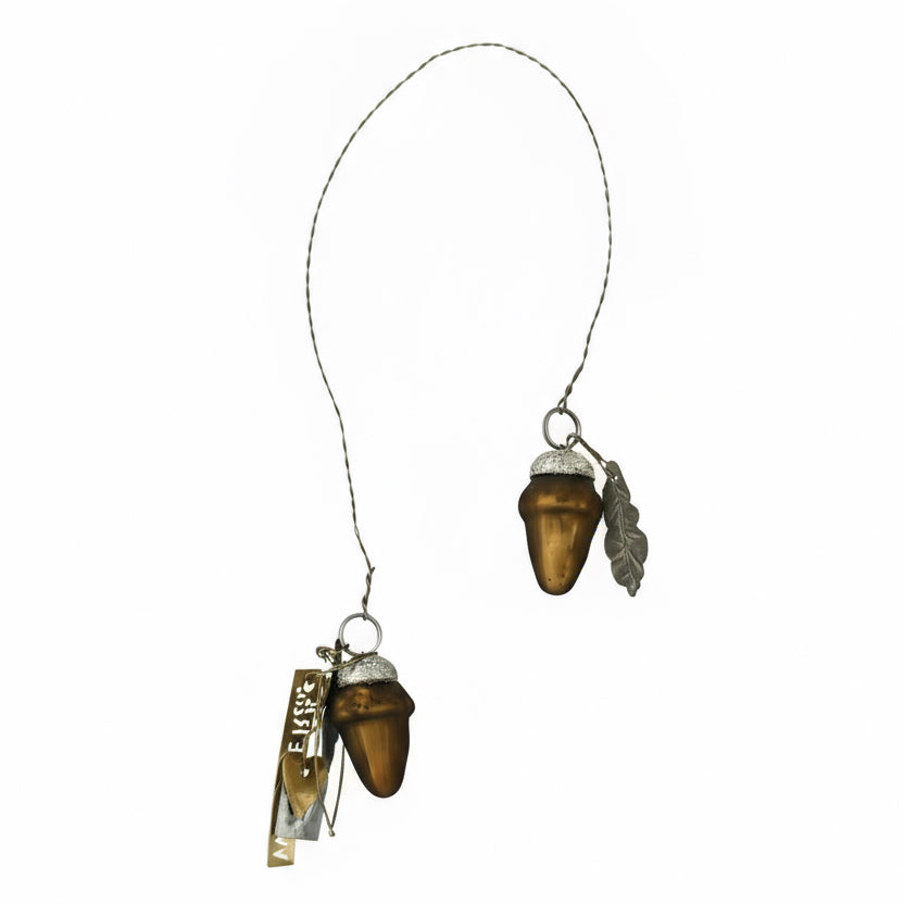Two acorn-shaped ornaments hanging on a string with a white background