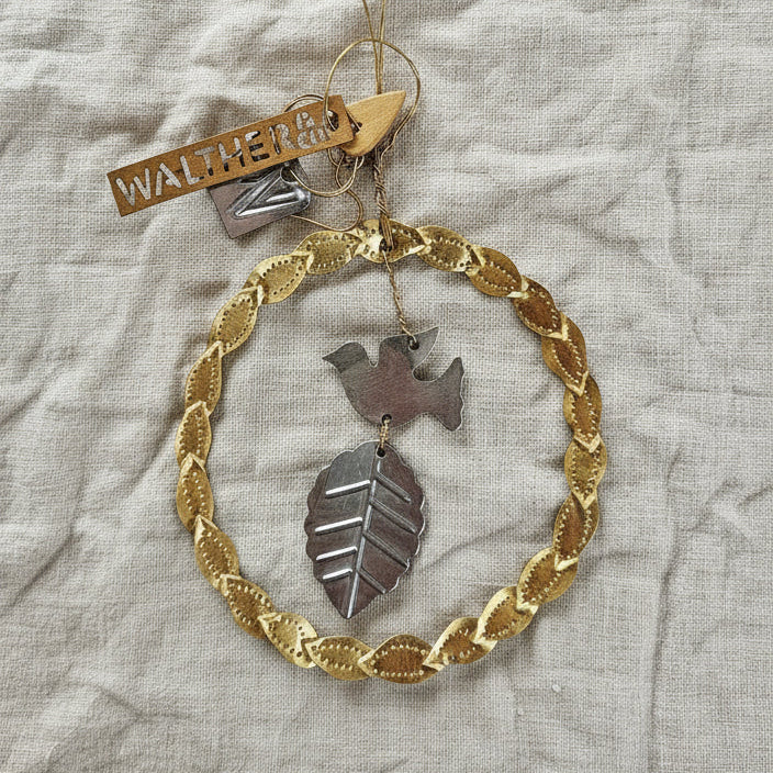 Decorative hanging ornament with gold chain and leaf design on a textured fabric background