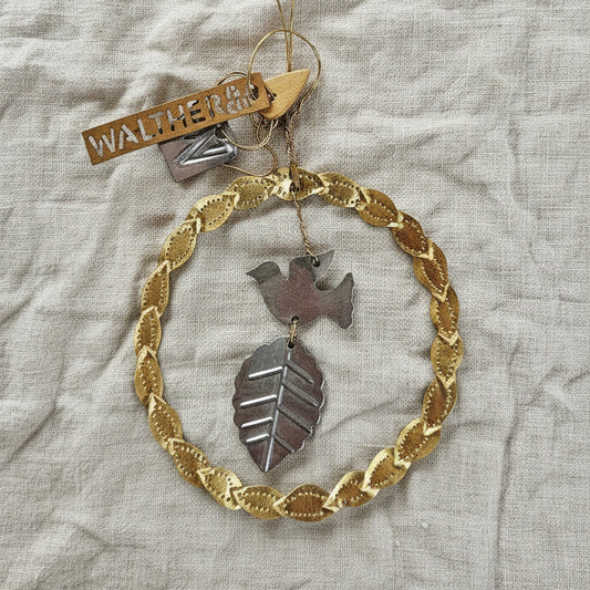 Decorative hanging ornament with gold chain and leaf design on a textured fabric background